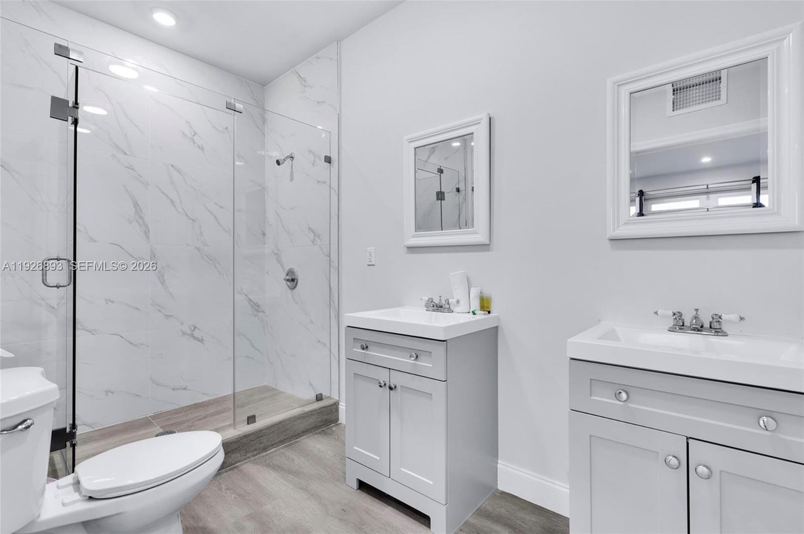 A bathroom features a glass-enclosed shower, two gray vanities, and light-colored wood-look flooring — 1968 NW 25th Ave, Miami FL 33125, MIAMI, FL