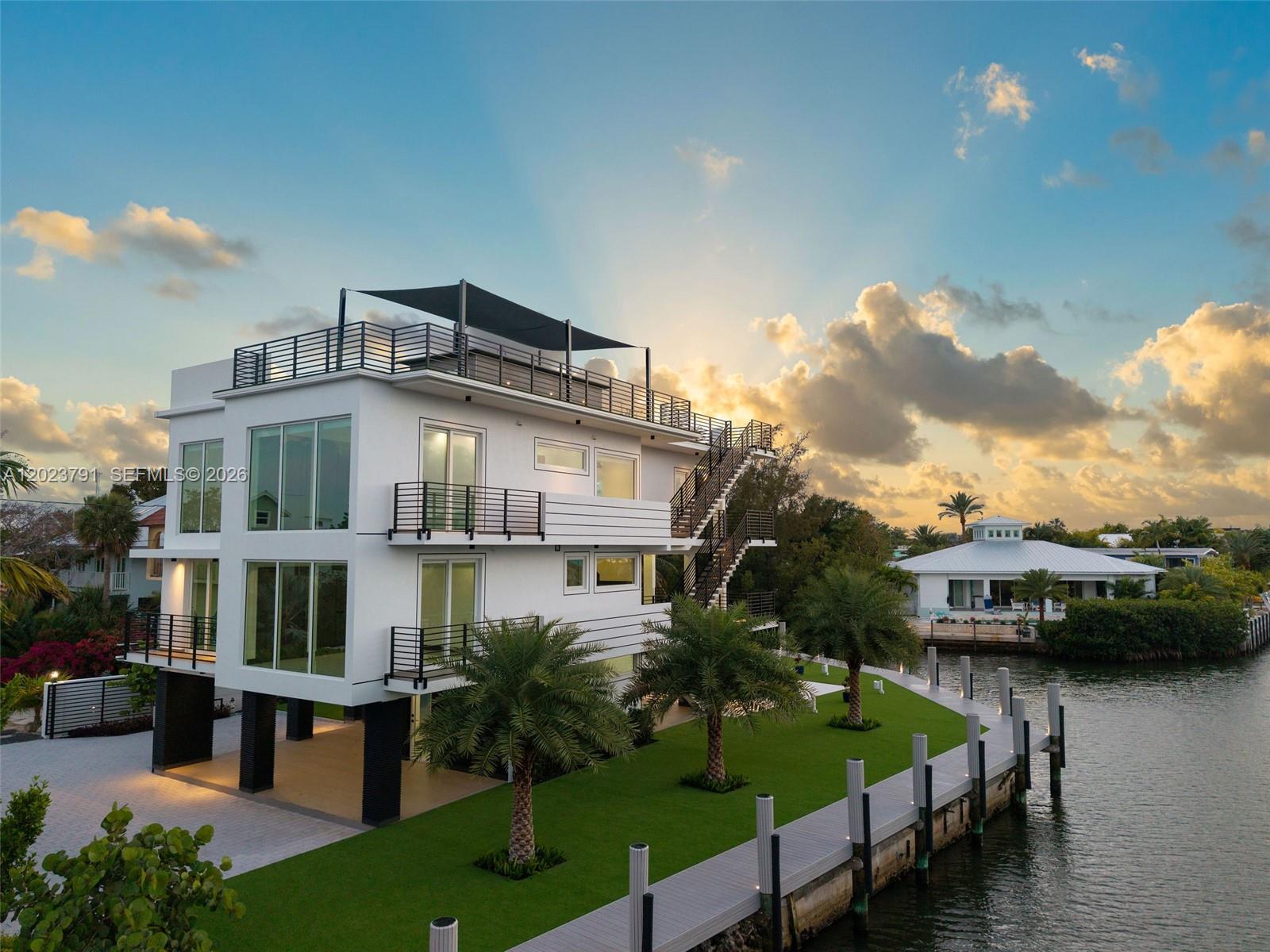 A modern multi-story white house with a rooftop deck sits beside a waterfront dock — 265 Pueblo St, Tavernier FL 33070, TAVERNIER, FL