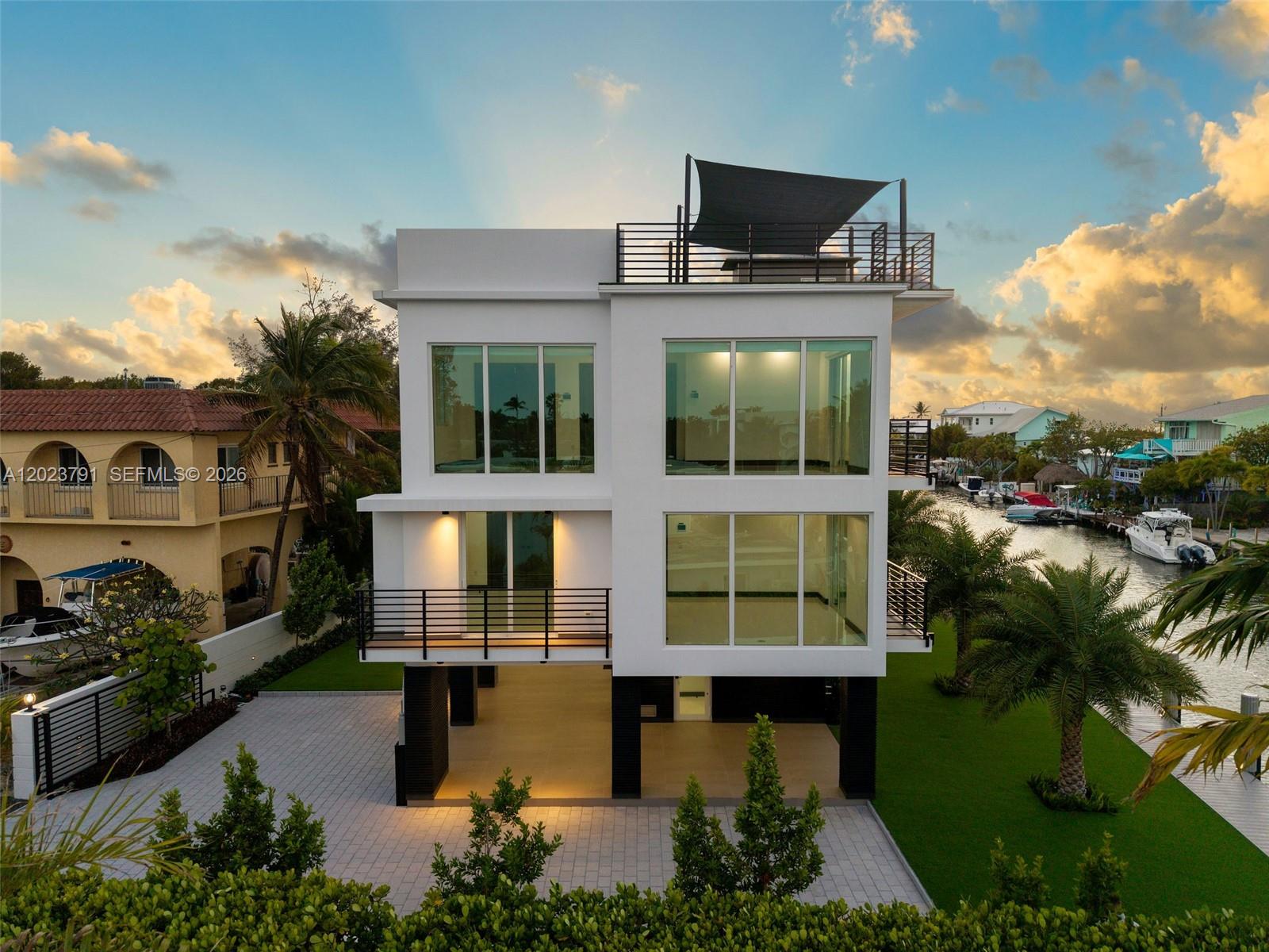 A modern three-story waterfront home with large windows, a rooftop deck, and an elevated ground level — 265 Pueblo St, Tavernier FL 33070, TAVERNIER, FL