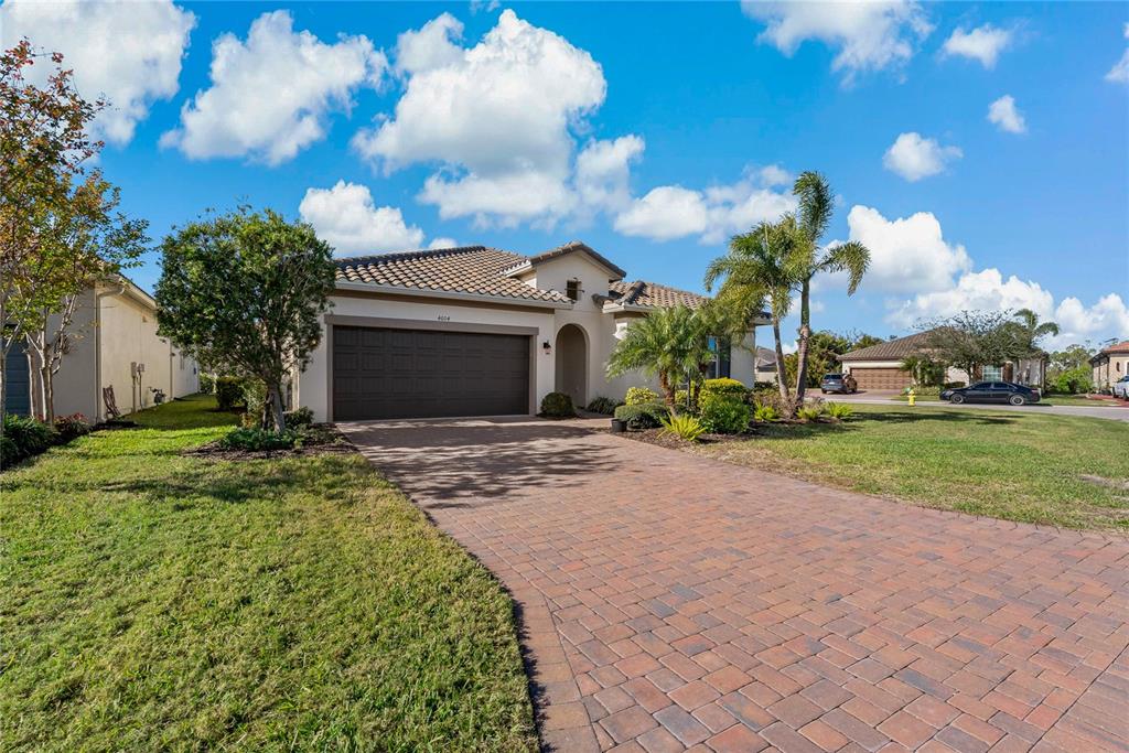 A single-story house with a brown garage door, tiled roof, and a brick paver driveway — 4604 TOBERMORY WAY, BRADENTON, FL