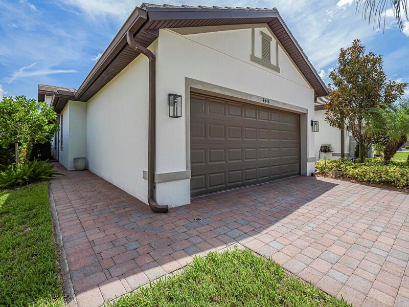 A single-story house exterior features a two-car garage, brick paver driveway, and stucco walls — VERO BEACH, FL