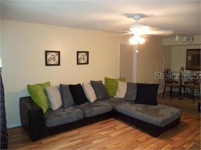 A living room features a large gray sectional sofa, hardwood floors, and a ceiling fan — 3004 PARKWAY BOULEVARD UNIT 208, KISSIMMEE, FL