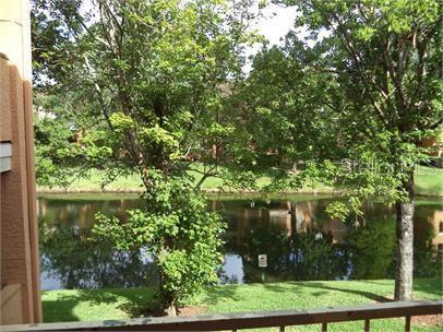 A view of a pond and trees from a balcony with a metal railing — 3004 PARKWAY BOULEVARD UNIT 208, KISSIMMEE, FL