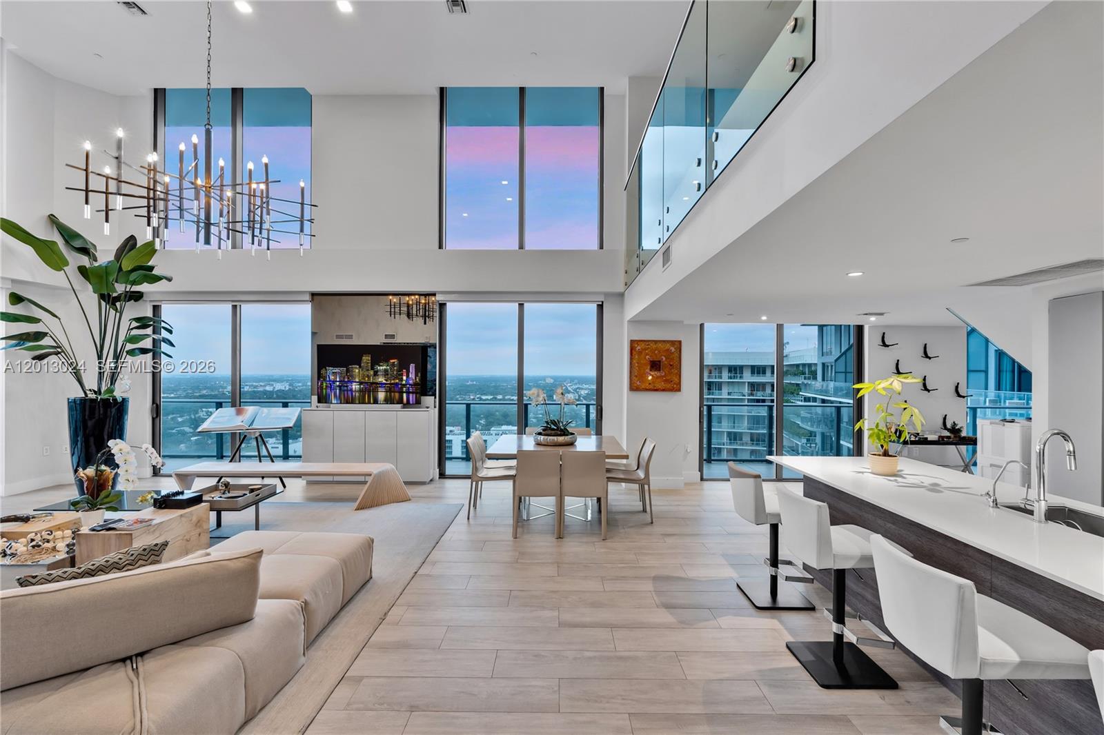 A modern, open-concept living and dining area features floor-to-ceiling windows and a lofted mezzanine — 121 NE 34th St, Miami FL 33137, MIAMI, FL