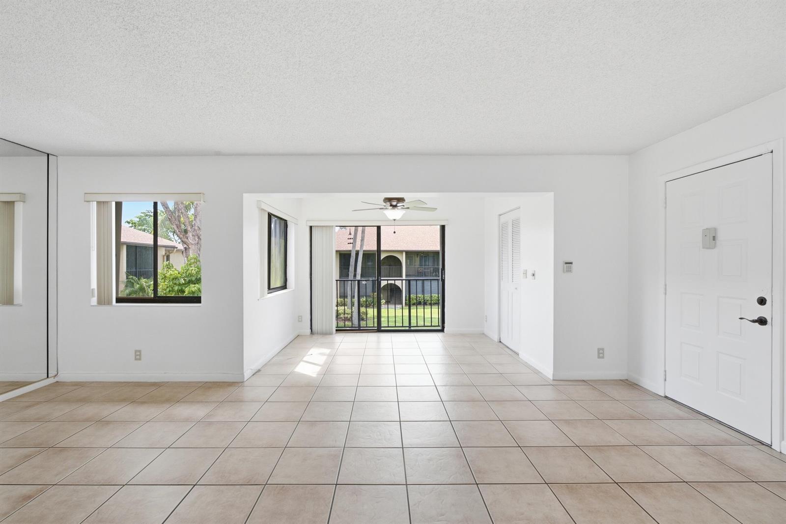 An empty living room with white walls, tile flooring, a ceiling fan, and sliding glass doors — 518 Shady Pine Way # B2, FL 33415, FL