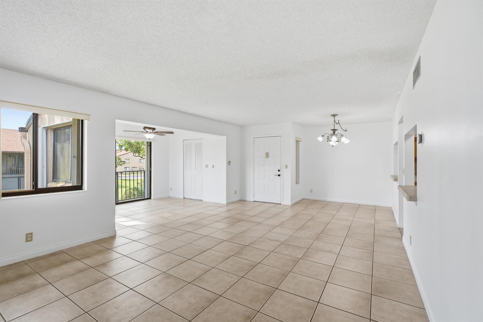 An open-concept living and dining area with beige tile floors, white walls, and a balcony — 518 Shady Pine Way # B2, FL 33415, FL