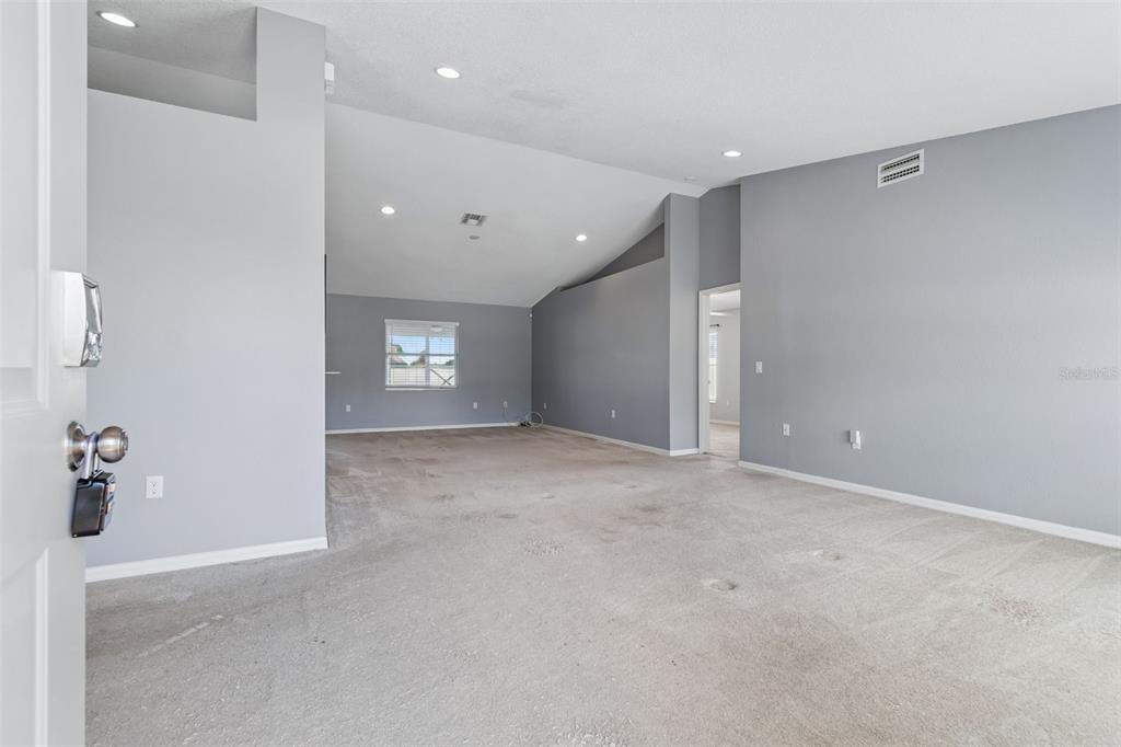 An empty room with gray walls, beige carpeting, and a vaulted ceiling with recessed lighting — 6352 PROMINENCE POINT DRIVE, LAKELAND, FL