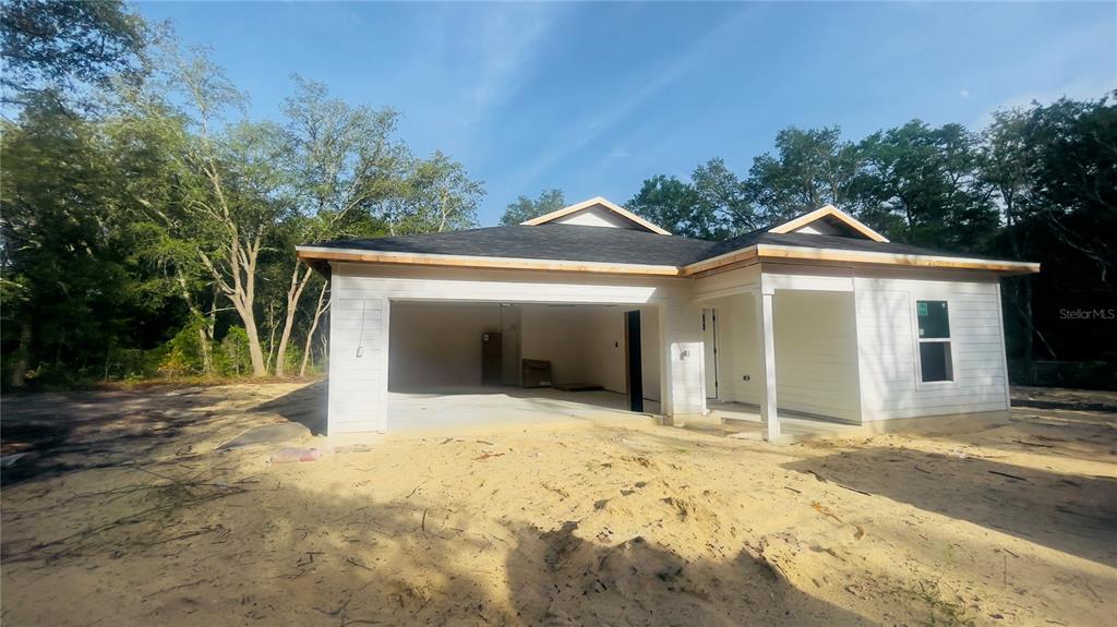 A newly constructed single-story house with white siding, a garage, and a covered porch — 8030 NE 102ND COURT, BRONSON, FL