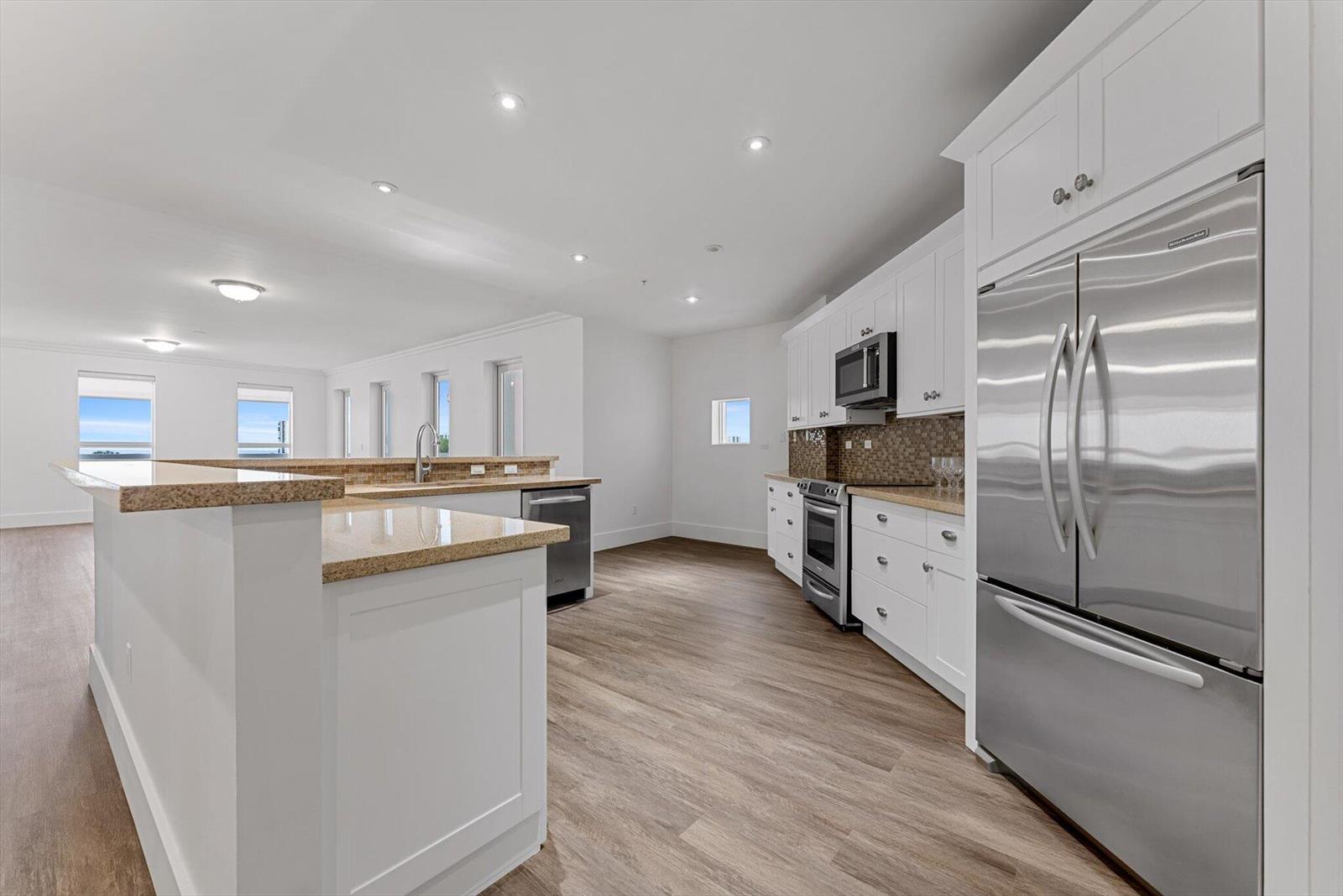 A kitchen features white cabinetry, stainless steel appliances, granite countertops, and wood-look flooring — 455 E Palmetto Park Road # 6e, Boca Raton FL 33432, BOCA RATON, FL