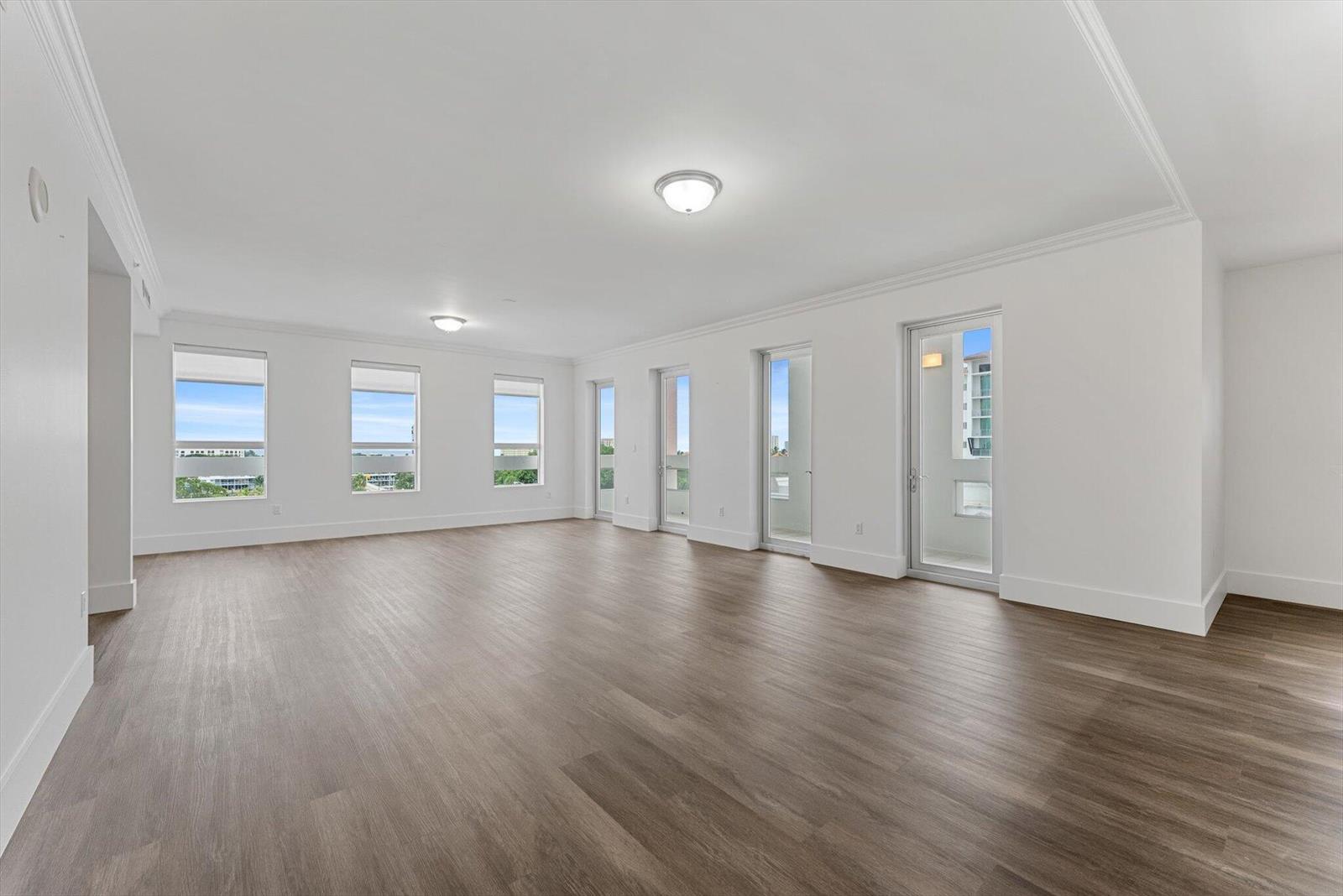 An empty room with white walls, wood-look flooring, multiple windows, and glass balcony doors — 455 E Palmetto Park Road # 6e, Boca Raton FL 33432, BOCA RATON, FL