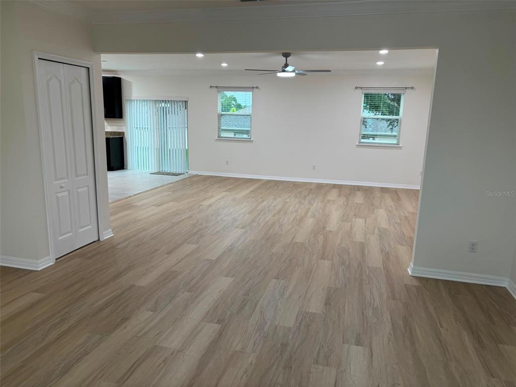 An open-concept living area features light wood-look flooring, white walls, and a ceiling fan — 1236 WATER WILLOW DRIVE, GROVELAND, FL