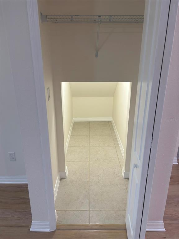 A small walk-in closet with tiled flooring and a wire shelf under a sloped ceiling — 1236 WATER WILLOW DRIVE, GROVELAND, FL
