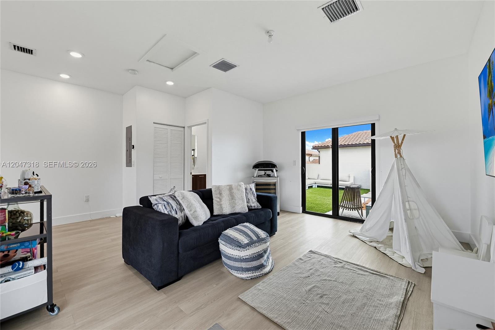 A living room with light wood floors, a dark sofa, and a white play tent — 4605 NW 83rd Path, Doral FL 33166, DORAL, FL