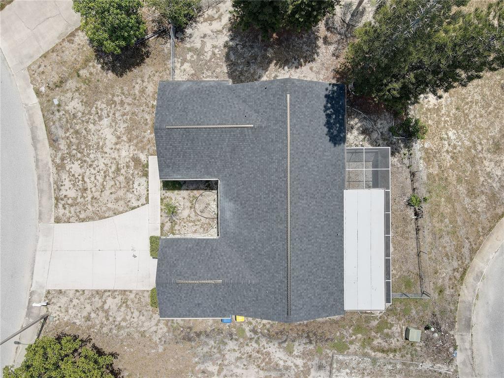 An aerial view shows a house with a dark shingled roof and a screened patio — 3718 PENRICK DRIVE, HOLIDAY, FL