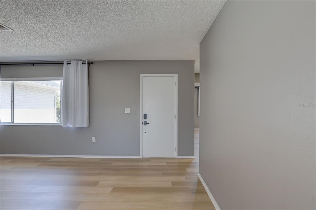 A room with light wood-look flooring, gray walls, a white door, and a window — 3718 PENRICK DRIVE, HOLIDAY, FL