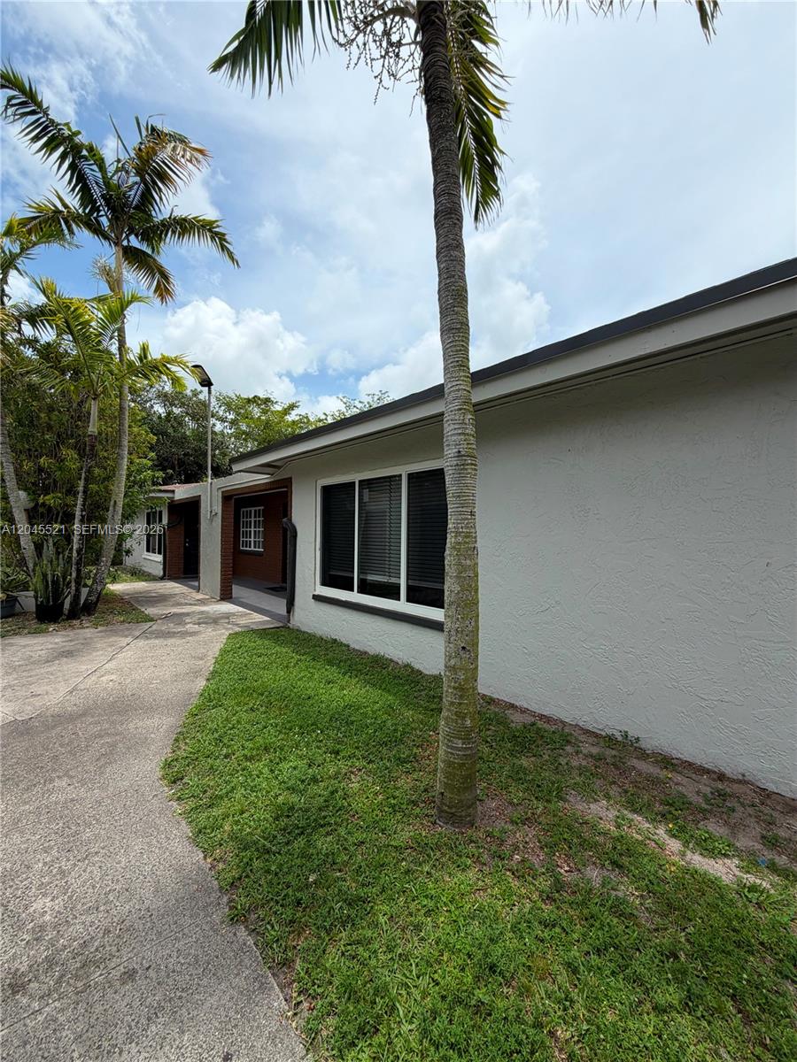 A concrete walkway leads to the side entrance of a house with a palm tree — 2551 NW 26th St, Sunrise FL 33313, SUNRISE, FL