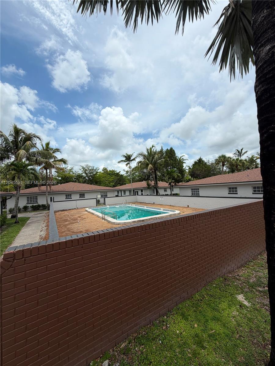 An outdoor swimming pool is enclosed by a low brick wall in a residential backyard — 2551 NW 26th St, Sunrise FL 33313, SUNRISE, FL