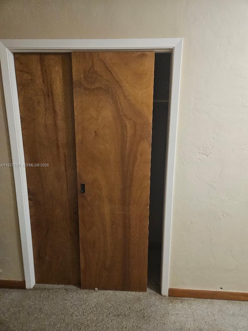 A closet with sliding wooden doors is set into a beige wall — 5842 Harding St # R, Hollywood FL 33021, HOLLYWOOD, FL