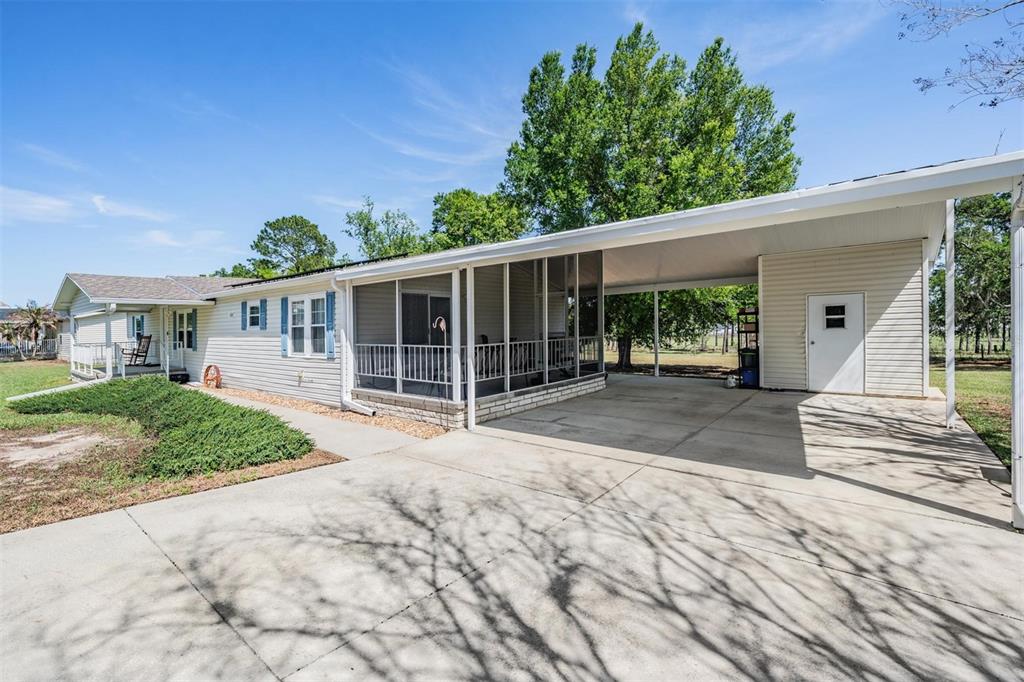 A single-story house features a screened-in porch, a concrete driveway, and an attached carport — 13544 KENT BRADLEY STREET, DADE CITY, FL