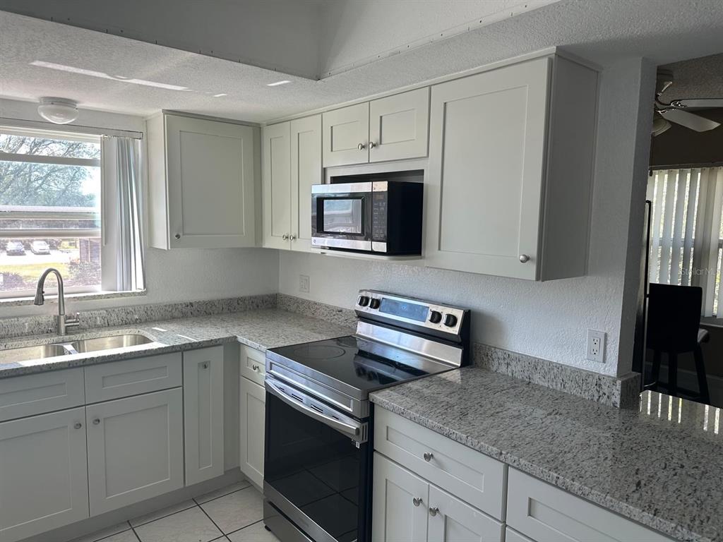 A kitchen features light-colored cabinets, granite countertops, stainless steel appliances, and a window — 2409 BARLEY CLUB DRIVE UNIT 3, ORLANDO, FL