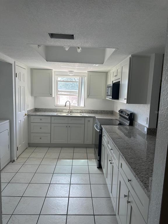 A kitchen with white cabinets, granite countertops, tile flooring, and a window above the sink — 2409 BARLEY CLUB DRIVE UNIT 3, ORLANDO, FL