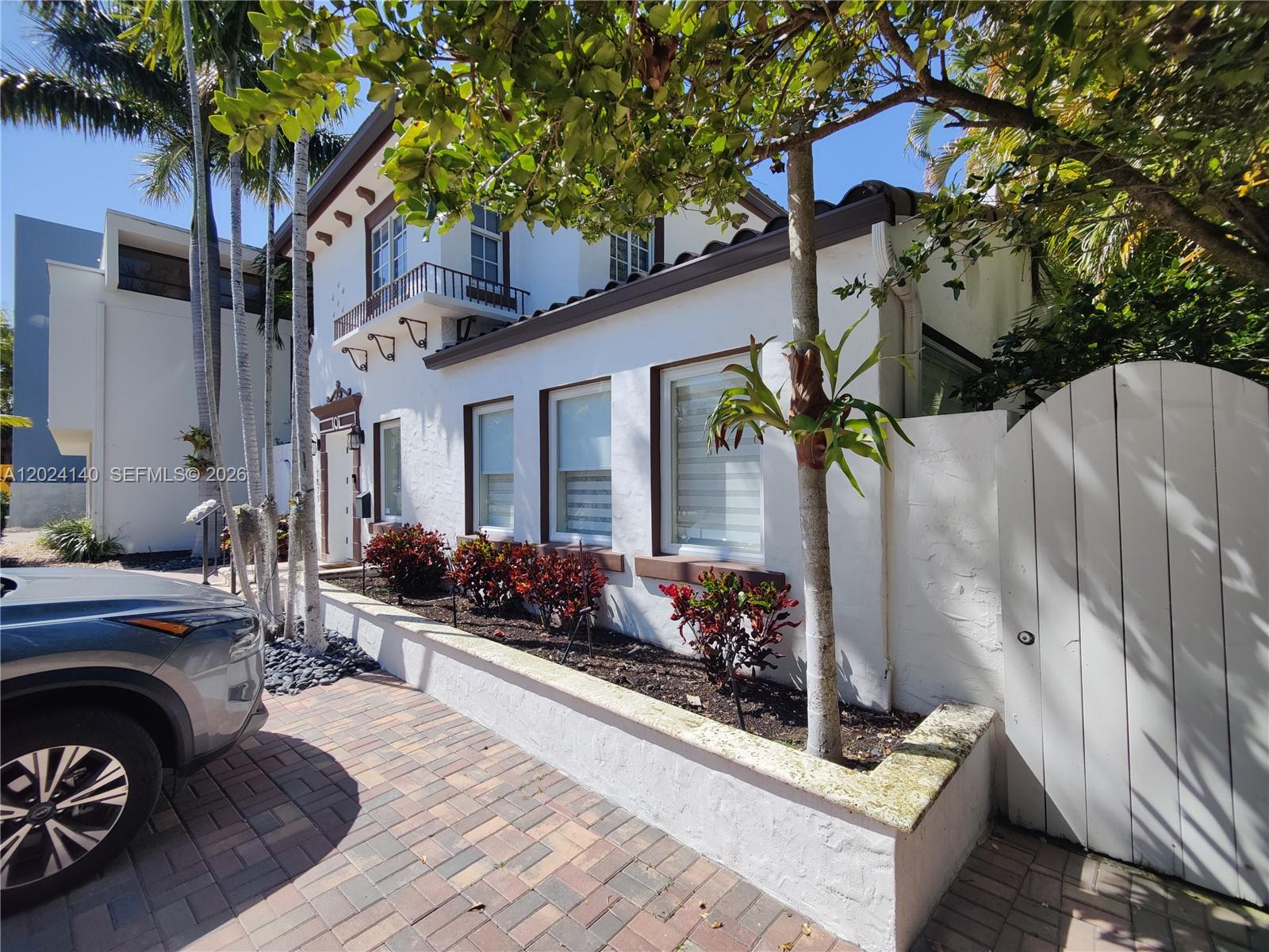 A white two-story house with a paved driveway, raised garden beds, and palm trees — 1823 S Bayshore Ln # 0, Miami FL 33133, MIAMI, FL