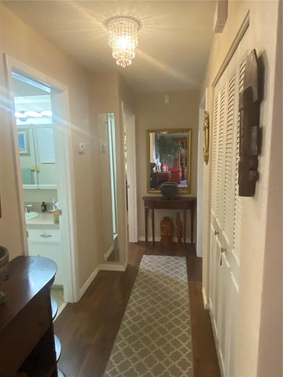 A hallway with hardwood floors, a patterned runner, a crystal light fixture, and a console table — 1657 N NORMANDY BOULEVARD, DELTONA, FL