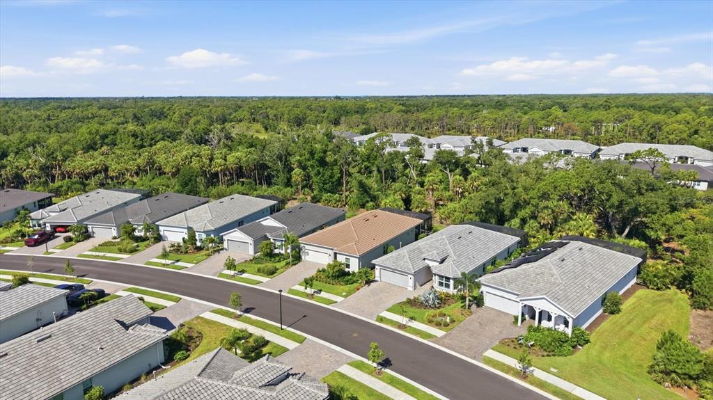 An aerial view shows a suburban neighborhood with single-story houses and surrounding wooded areas — 29248 CORAL HARBOUR DRIVE, ENGLEWOOD, FL