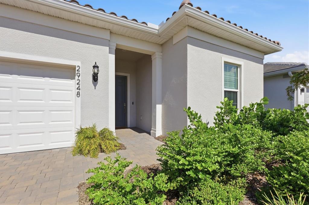 The exterior of a house features a garage, a covered entryway, and landscaped bushes — 29248 CORAL HARBOUR DRIVE, ENGLEWOOD, FL