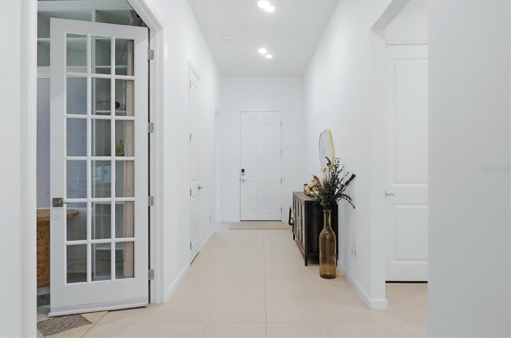 A bright entryway features white walls, tiled floors, a glass-paneled door, and a console table — 29248 CORAL HARBOUR DRIVE, ENGLEWOOD, FL