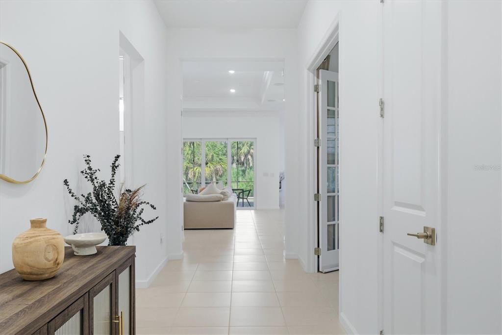 A bright hallway with white walls and tile flooring leads toward a living area — 29248 CORAL HARBOUR DRIVE, ENGLEWOOD, FL
