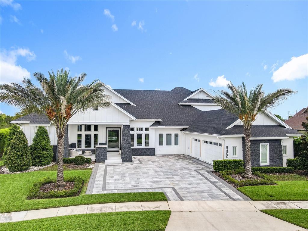 A modern white house with dark stone accents, a paved driveway, and two palm trees — 8600 HATA STREET, ORLANDO, FL
