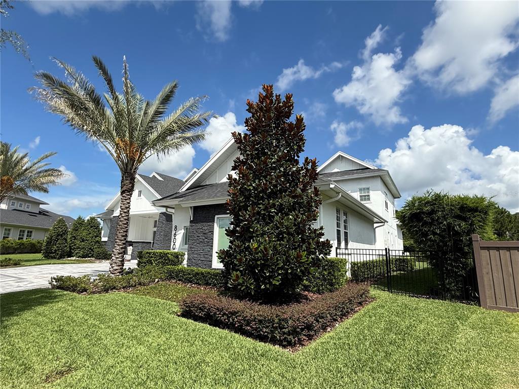 A two-story house with white siding, dark stone accents, a palm tree, and landscaping — 8600 HATA STREET, ORLANDO, FL