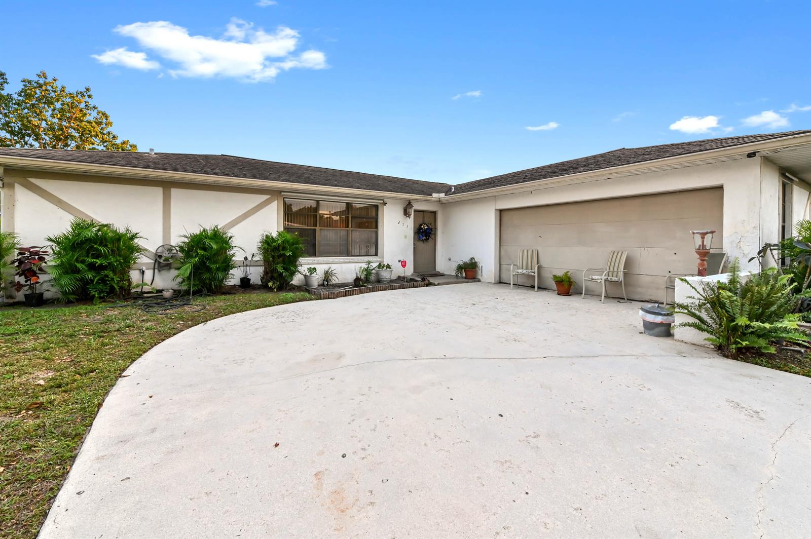 A single-story house exterior features a concrete driveway, a two-car garage, and landscaping — 2531 Doral Way, Riviera Beach FL 33407, RIVIERA BEACH, FL