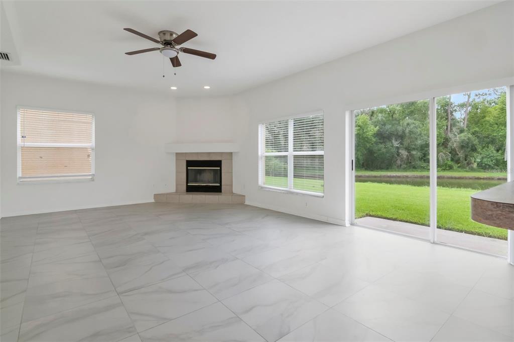 A living room features white tile floors, a corner fireplace, and sliding glass doors to outdoors — 27512 BREAKERS DRIVE, WESLEY CHAPEL, FL