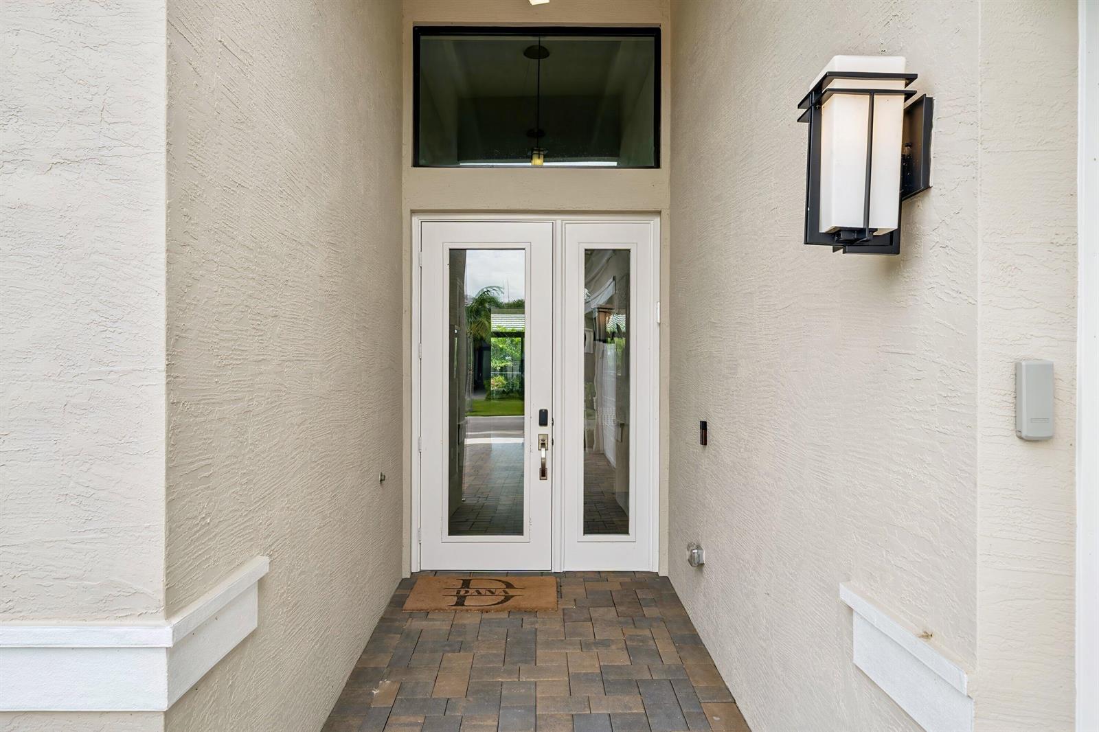 A white front door with glass panels sits at the end of a paved entryway — 9812 Spruce Woods Drive, Boynton Beach FL 33473, BOYNTON BEACH, FL