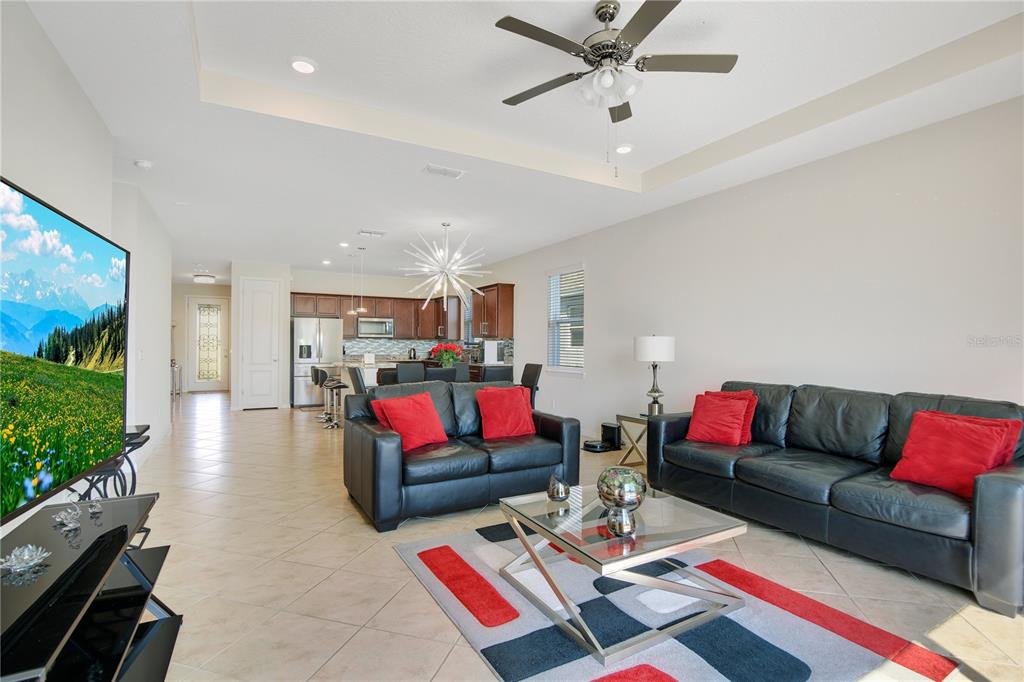 A living room with black leather sofas and a kitchen with dark wood cabinets — 5133 CHICKADEE STREET, ST CLOUD, FL
