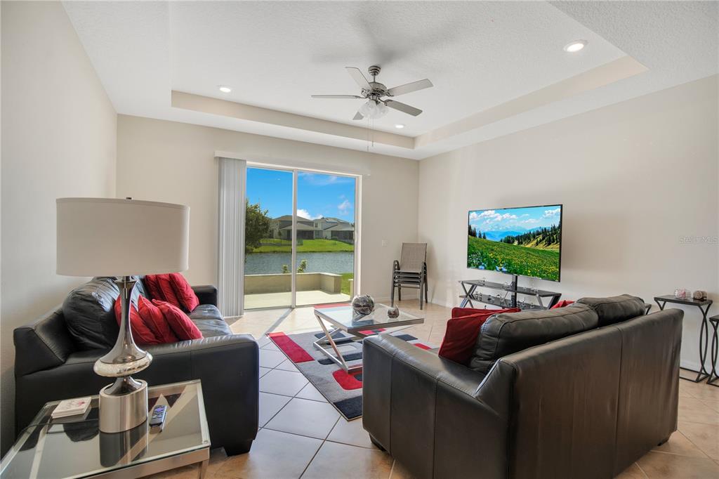A living room with black leather sofas, a glass coffee table, and sliding glass doors — 5133 CHICKADEE STREET, ST CLOUD, FL