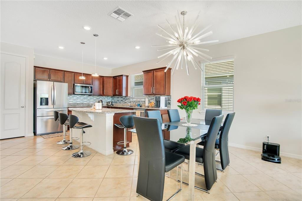 A kitchen and dining area with dark wood cabinets, granite countertops, and a starburst chandelier — 5133 CHICKADEE STREET, ST CLOUD, FL