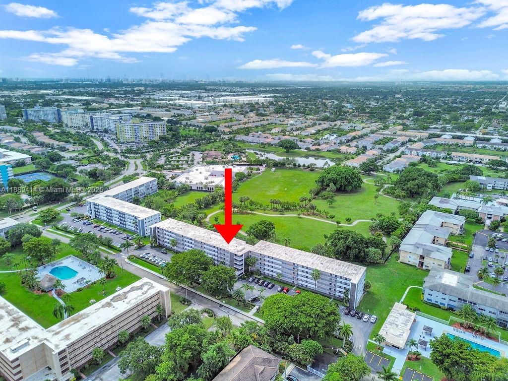 An aerial view shows a multi-story apartment building with a red arrow pointing downward — 4800 Hillcrest Ln # 210, Hollywood FL 33021, HOLLYWOOD, FL
