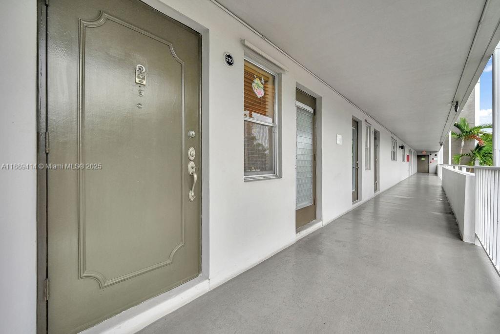 An exterior walkway leads past a tan door with a decorative frame and a window — 4800 Hillcrest Ln # 210, Hollywood FL 33021, HOLLYWOOD, FL