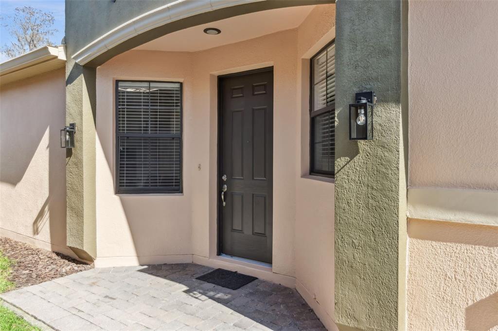 A front entryway features a dark door, two windows with blinds, and two black light fixtures — 884 GRAND CANAL DRIVE, KISSIMMEE, FL