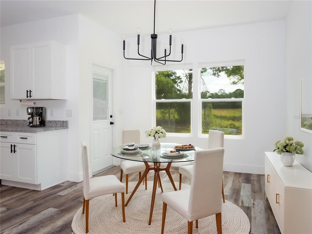 A dining area features a glass table, four chairs, a chandelier, and a white cabinet — 217 SW 246TH WAY, NEWBERRY, FL