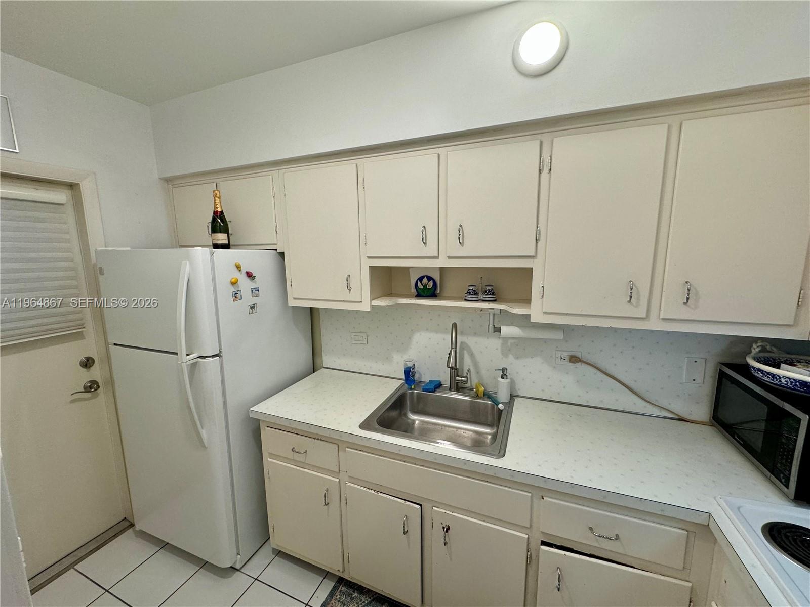 A kitchen features white cabinets, a stainless steel sink, and a white refrigerator — 6580 Santona St # A38, Coral Gables FL 33146, CORAL GABLES, FL