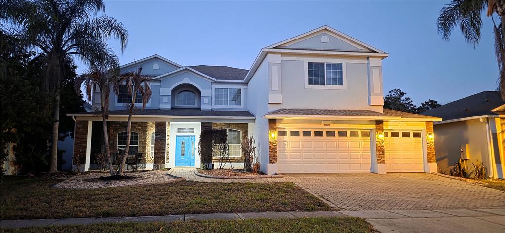 A two-story house with a light blue exterior, stone accents, and a three-car garage — 10021 HART BRANCH CIRCLE, ORLANDO, FL