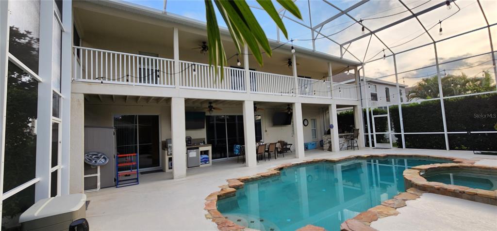 A two-story house exterior features a screened-in pool, a hot tub, and a covered patio — 10021 HART BRANCH CIRCLE, ORLANDO, FL