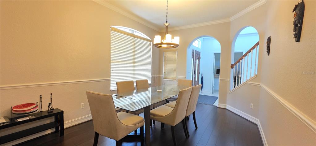 A dining room features a glass table, upholstered chairs, dark wood floors, and arched entryways — 10021 HART BRANCH CIRCLE, ORLANDO, FL