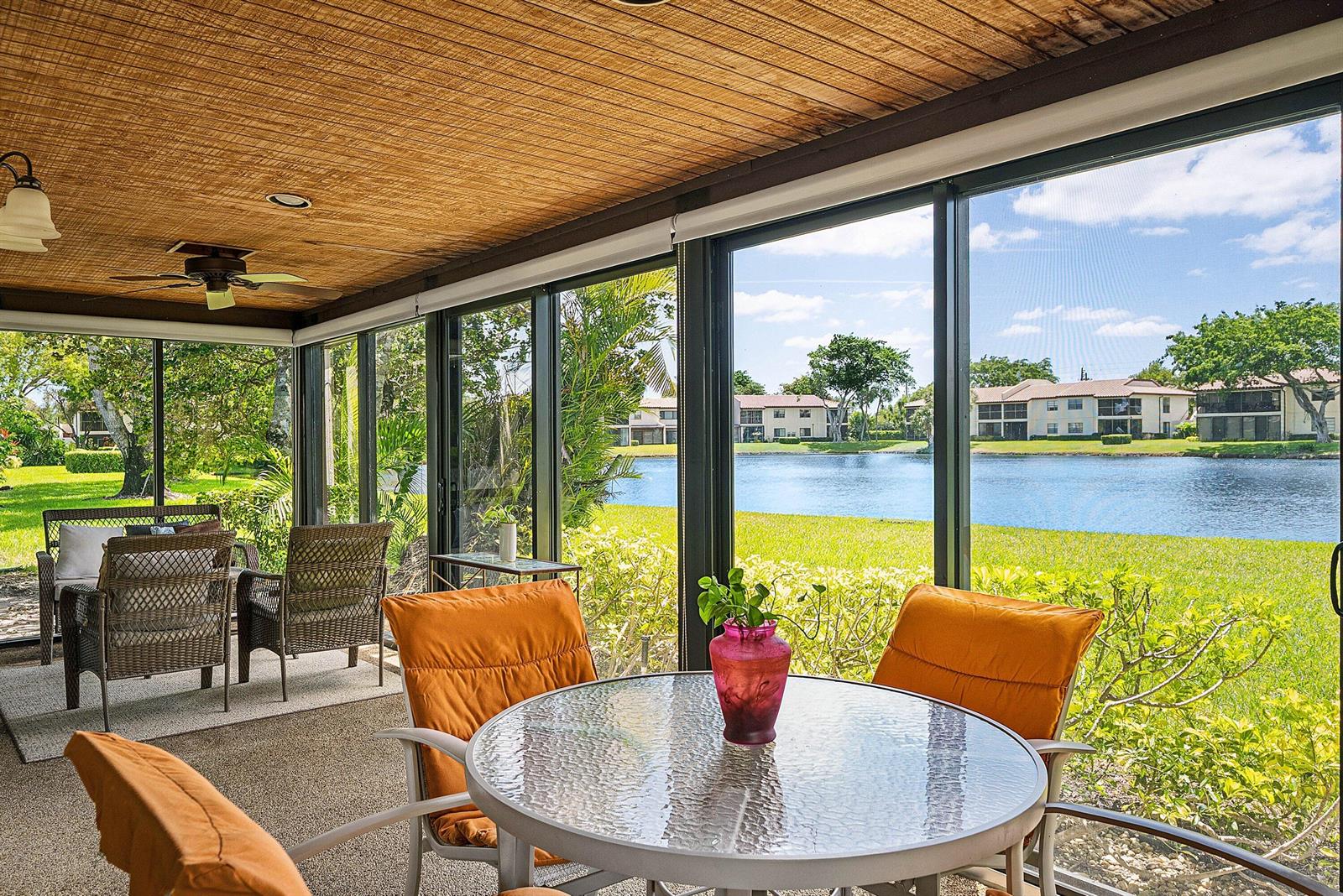 A screened-in patio features a dining set, wicker chairs, and views of a lake — 21875 Arriba Real # 18b, Boca Raton FL 33433, BOCA RATON, FL