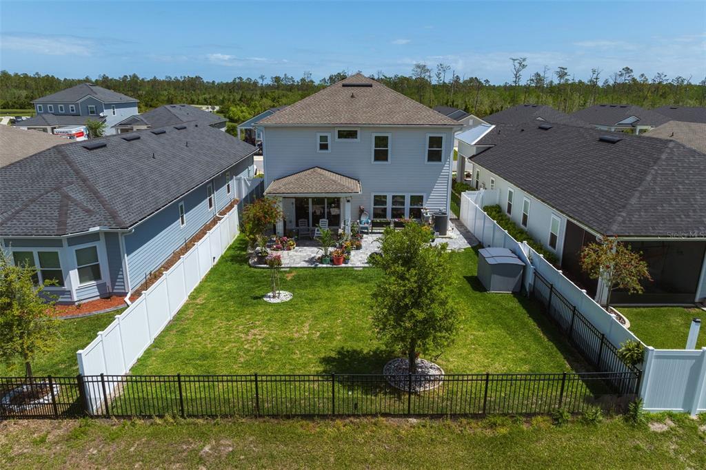 An aerial view of a two-story house with a fenced backyard and a paved patio — 121 NIGHTHAWK LANE, PALM COAST, FL