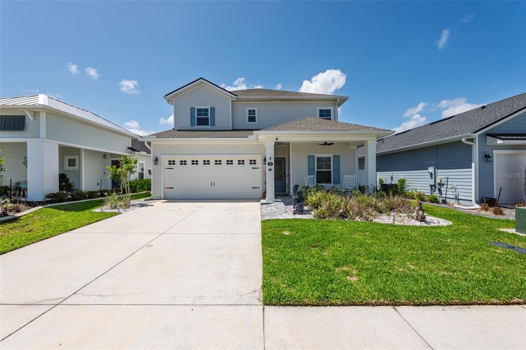 A two-story suburban house with a white garage, front porch, and a grassy lawn — 121 NIGHTHAWK LANE, PALM COAST, FL